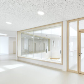 Das Bild zeigt einen modernen, minimalistisch gestalteten Innenraum mit weißen Wänden und einer Decke mit Punktmuster und eingelassener Beleuchtung. In der Mitte befindet sich ein großes Glasfenster mit Blick in einen angrenzenden Raum, rechts daneben eine Tür mit Holzrahmen und Glaseinsatz. Links ist eine in die Wand integrierte, eckige Fenstersitzbank zu sehen.