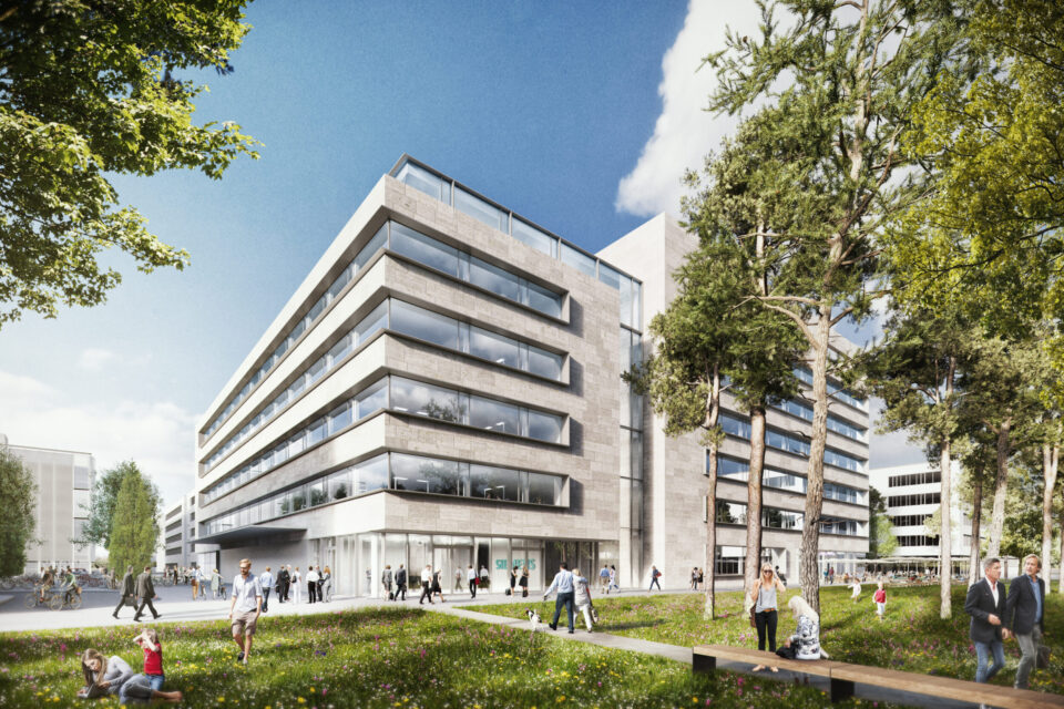 Das Bild zeigt ein modernes, mehrstöckiges Bürogebäude mit großen Glasfenstern und einer Fassade aus Beton. Um das Gebäude herum befindet sich eine gestaltete Grünfläche mit Rasen, Bäumen und Menschen, die spazieren gehen oder auf dem Gras sitzen. Der Himmel ist überwiegend klar mit einigen Wolken, was auf einen sonnigen Tag hinweist.