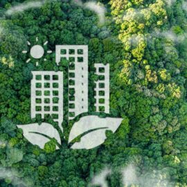 Das Bild zeigt eine Draufsicht auf einen dichten grünen Wald, in dem eine große grafische Darstellung integriert ist. Die Grafik besteht aus drei stilisierten Hochhäusern, die von zwei Blättern umrahmt werden, sowie einer Sonne über den Gebäuden. Die Gestaltung symbolisiert die Verbindung von urbanem Bauen mit Natur und Nachhaltigkeit.