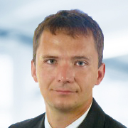 Heiko Krämer trägt einen Anzug. Der Hintergrund ist unscharf und zeigt ein Büro.