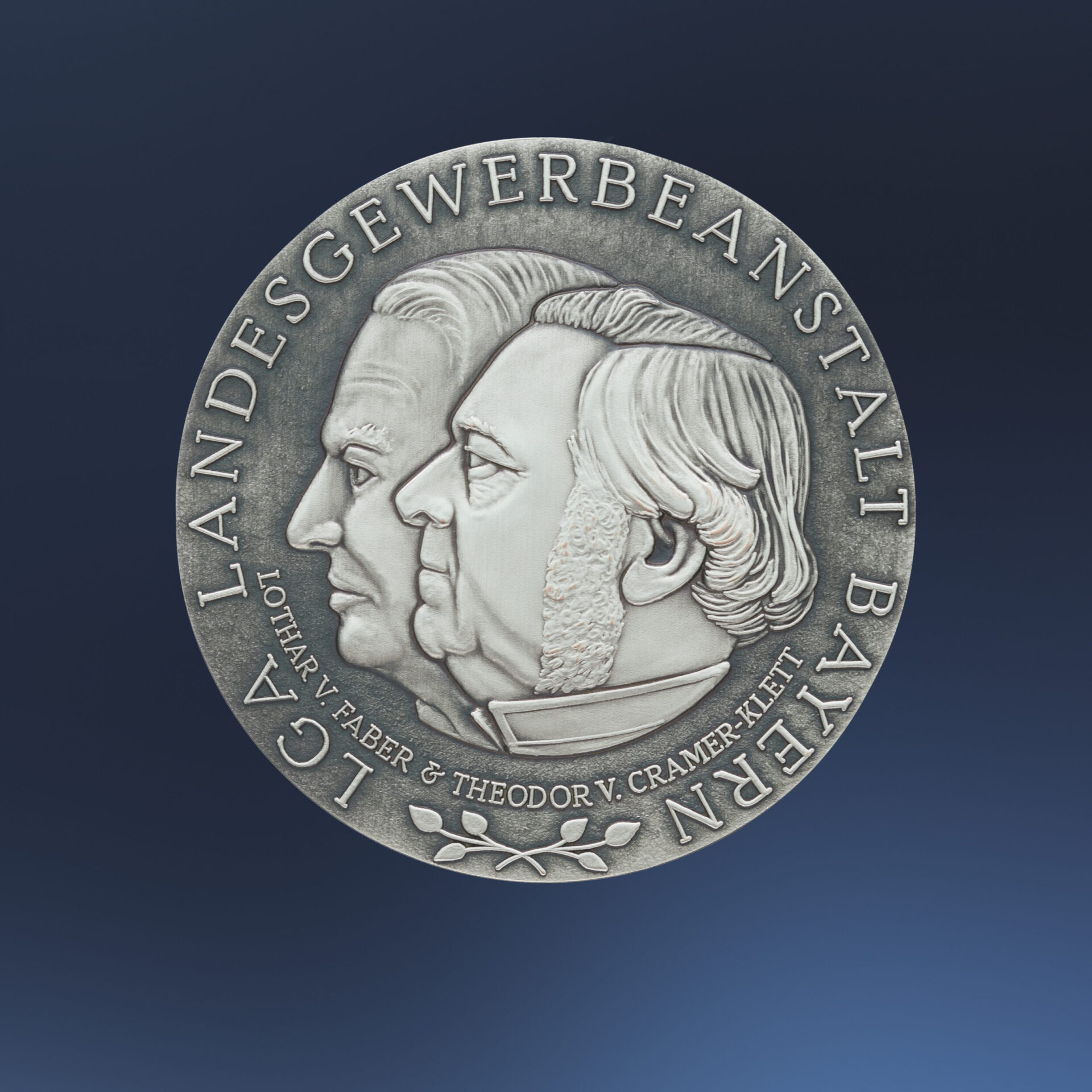Silberne Medaille auf blauem Hintergrund mit dem geprägten Profil zweier Köpfe in der Mitte, umgeben von der Inschrift „LGA LANDESGEWERBEANSTALT BAYERN“ und „LOTHAR V. FABER & THEODOR V. CRAMER-KLETT“.