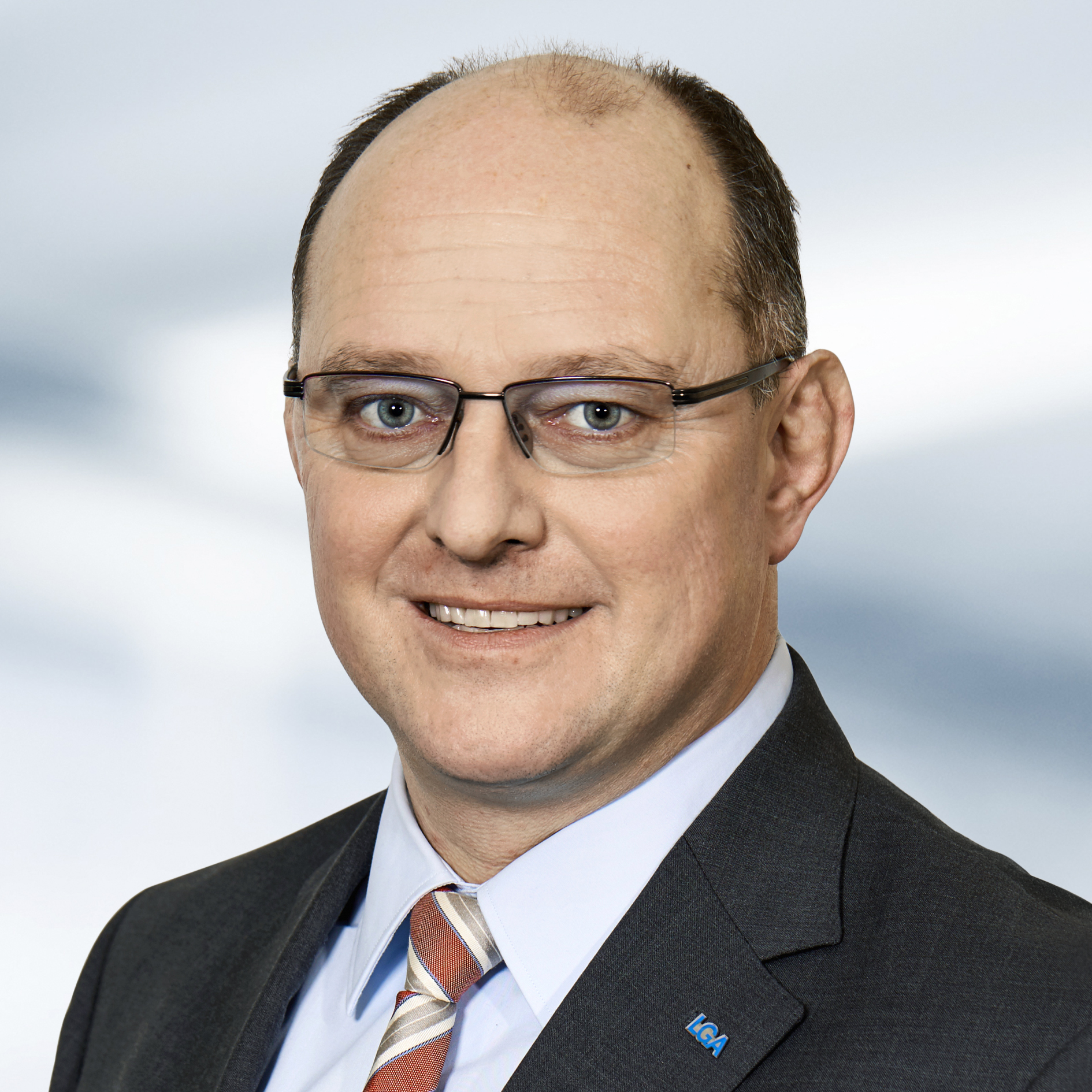 Kai-Uwe Richter trägt einen Anzug und eine Krawatte. Der Hintergrund ist unscharf und zeigt ein Büro.