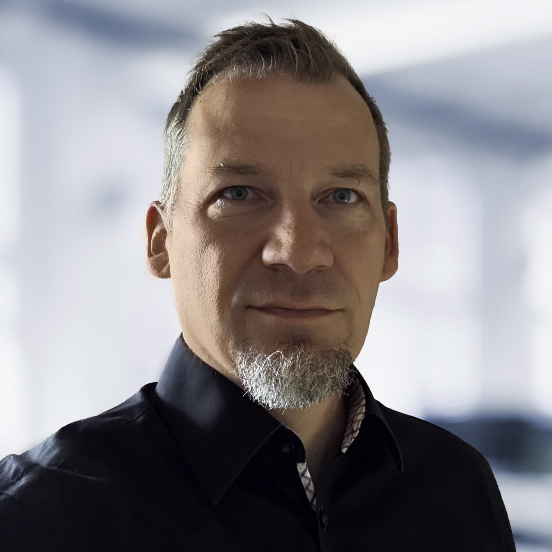 Michael Wahl trägt eine schwarzes Hemd. Der Hintergrund ist unscharf und zeigt ein Büro.
